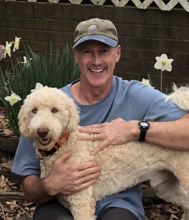 A smiling man with his blonde colored dog